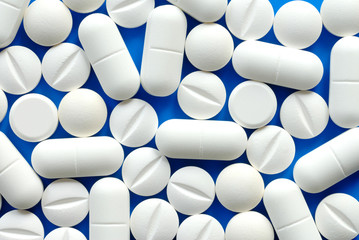 Macro of white pills on blue background