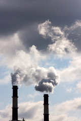 Two chimneys from which there is a smoke against the sky