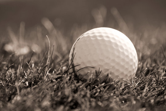 Sepia toned close-up of golfball in grass