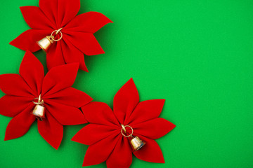 Three red poinsettias with bells on green background