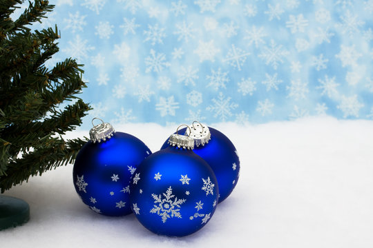 Blue glass Christmas balls and tree on snow with snowflake