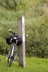 touring bicycle leaning against wooden post