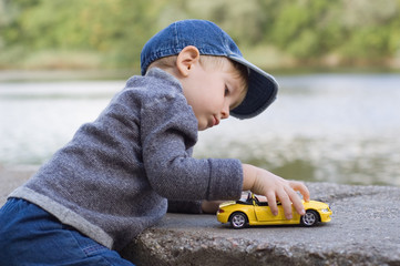 little boy play with a car outdoor