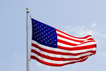 An american flag blowing in the wind with bright sunlight