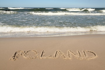 Poland - country name drawn on a sandy beach