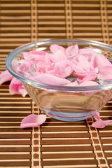 Bowl with rose petals on a wooden napkin