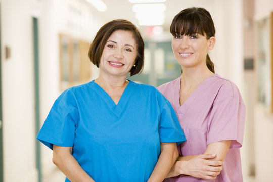 Two Female Nurses Standing In A Hospital Corridor