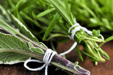Bunches of assorted fresh herbs close up on wooden cutting board
