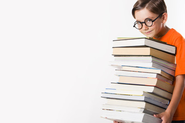 Photo of clever preschooler holding heavy pile of books