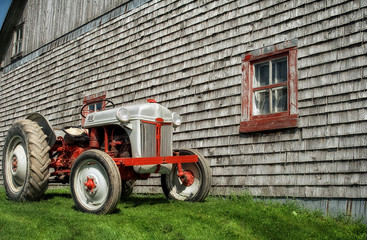 An old tractor in front of a barn