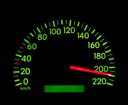 Speedometer of a car showing 210, glowing in the dark