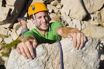 A rock climber desperately clinging to a cliff.