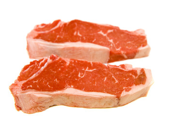 Two fresh strip steaks on a white background