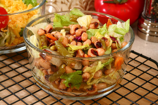 Glass bowl of black eye pea salad in kitchen or restaurant.