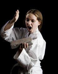 Young girl karate chopping a brick on black background © Scott Griessel