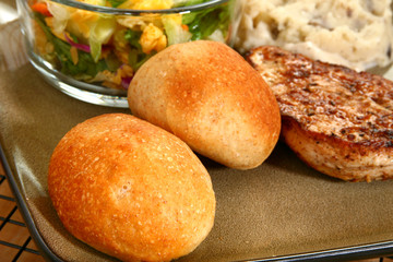 Dinner rolls in plate with chicken and potatoes.