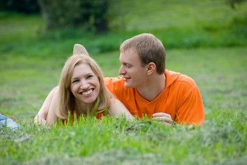 Loving couple lies and embraces on a green grass