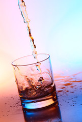 The stream filling an empty glass by alcohol