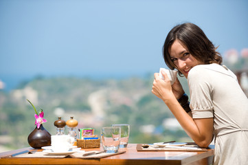 A young woman sitting alone at breakfast table