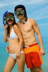 A young couple with snorkelling gear on a tropical beach