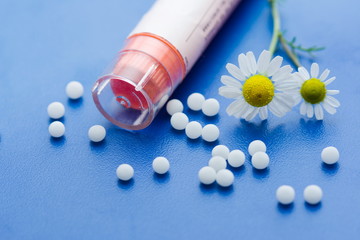 Chamomile flower and homeopathic medication on blue surface - obrazy, fototapety, plakaty