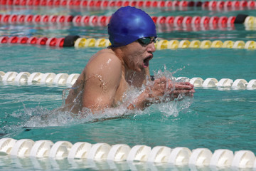 Male swimmer with blue cap doing breaststroke