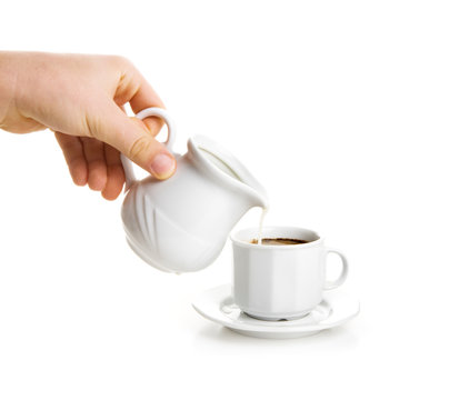 Milk stream flowing down in cup of coffee.