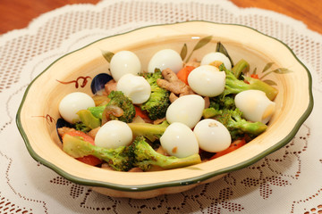 broccoli with quail eggs served in a bowl.