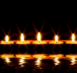 row of candles reflected in the water - 9420268