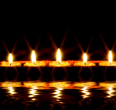 row of candles reflected in the water