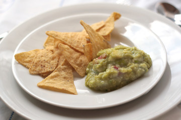 guacamole con nachos in un piatto bianco con sottopiatto