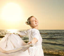 Fototapeta na wymiar Beautiful young woman dancing on a beach at sunset
