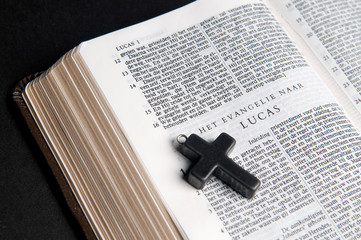 Closeup of Dutch Bible with cross, on black background.