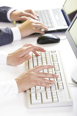 Image of human hands typing on white keyboards in row