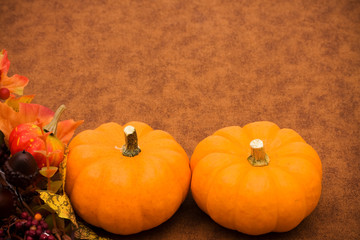 Fall leaves with orange gourd on brown background
