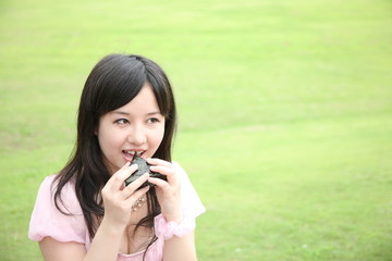 young asian woman eats a rice ball