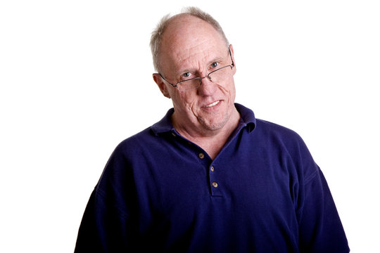 An Older Bald Guy Smiling Over His Reading Glasses