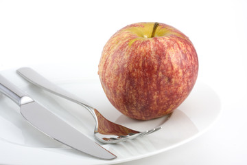 cutlery and an apple on a plate