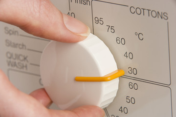 Person Adjusting Washing Machine Dial To Cold Wash