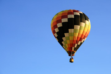 Multicoloured hot air balloon in the blue sky.