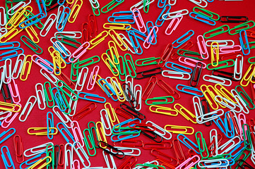 Colorful paperclips on red background