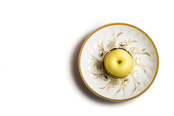 fresh yellow apple on white plate with pattern