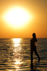 Silhouette of the young woman on a bay on a sunset