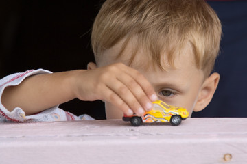 the little boy plays a toy car