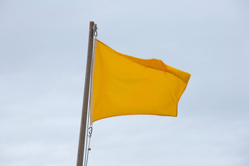 Yellow flag on the beach waving in the wind