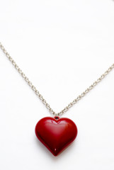 A silver necklace with a large heart shaped pendant