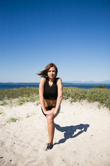 A caucasian girl stretching before exercising on the beach