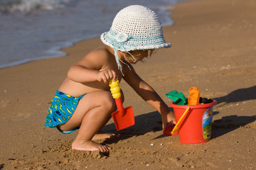 Fototapeta little girl in the bonnet plaing with sand, childhood obraz