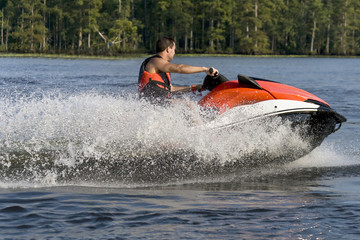 Man riding a wave runner in a river enjoying a nice summer day.