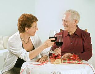 senior couple having wine and exchanging gifts